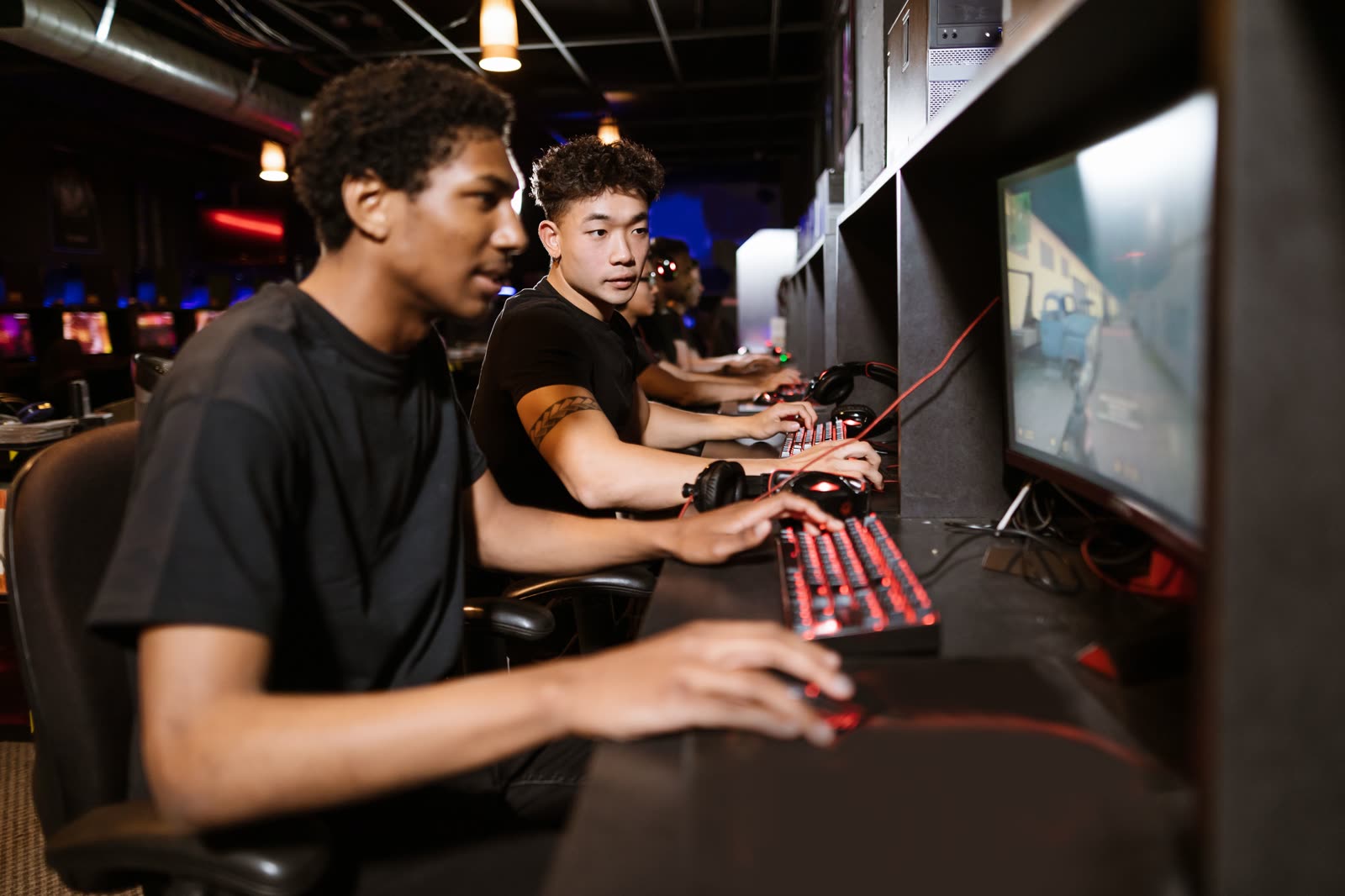 Two players seated side by side at neighbouring stations, lit by their screens